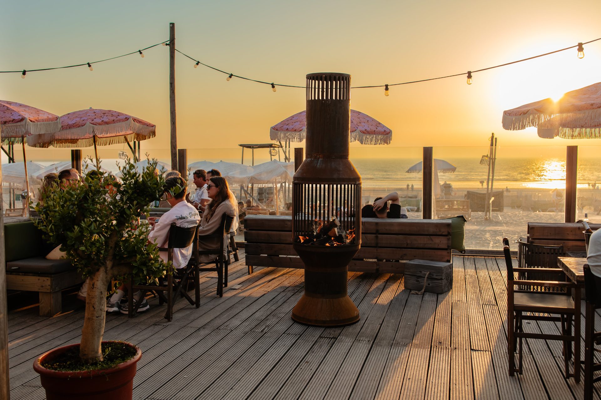 VENTOR Original buitenhaard van cortenstaal op het terras van een beachclub bij zonsondergang